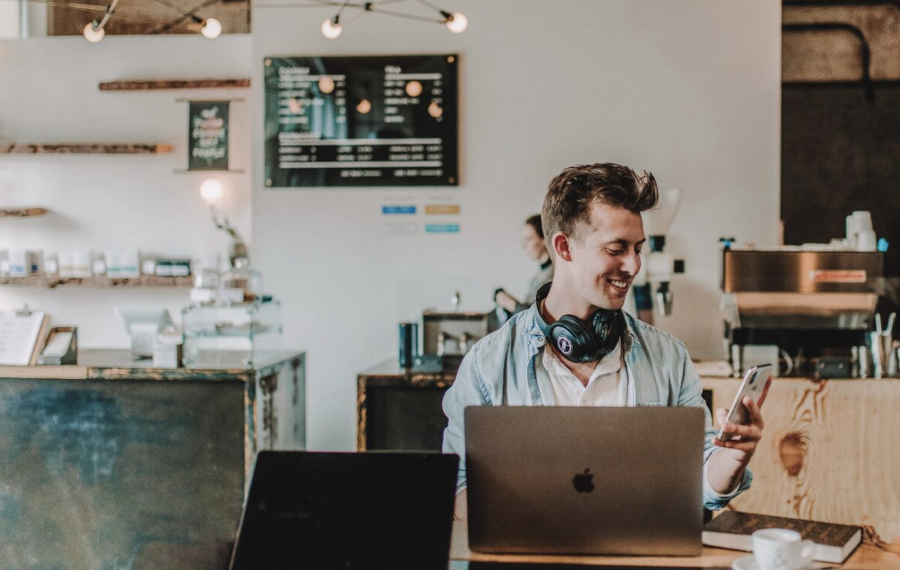 Jeune homme dans un café, travaillant depuis son ordinateur portable © Austin Distel